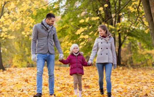 una familia paseando por un parque en el otoño