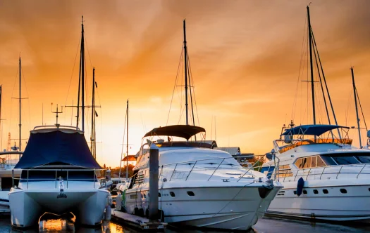 barcos y yachtas aparcados en el puerto con el cielo naranjo