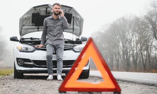 hombre atrapado al costado de la carretera hablando por teléfono